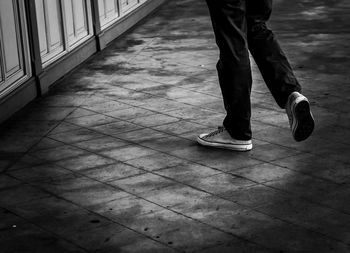 Low section of man walking on tiled floor