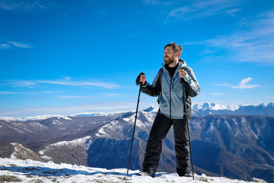 View of man standing on snowcapped mountain against sky