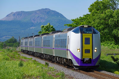 Train on railroad track by mountains against sky