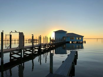 Pier on sea against clear sky during sunset