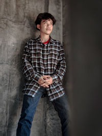 Portrait of young man standing against wall