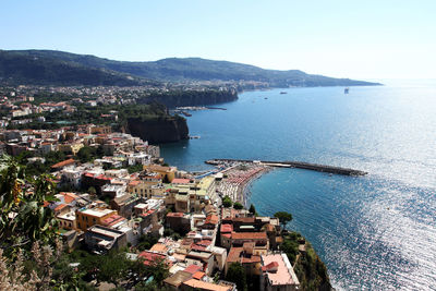 High angle view of town by sea against clear sky