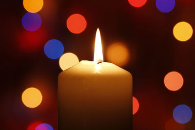 Close-up of lit candles in darkroom