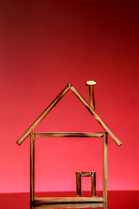 Close-up of wooden model home against red background