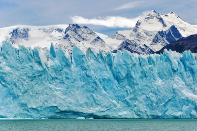 Scenic view of sea and snowcapped mountains against sky