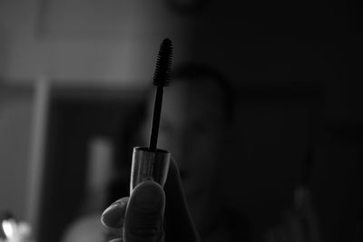 Close-up of hand holding cross against blurred background