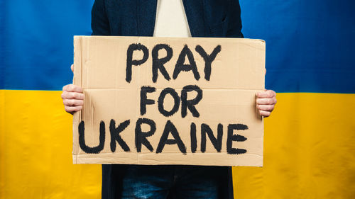 Boy holds in hand cardboard with inscription pray for ukraine