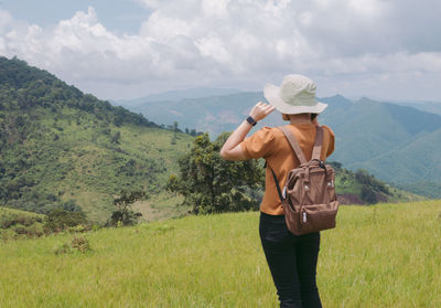 Rear view of woman wearing hat standing against landscape