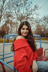 Beautiful young woman sitting on outdoor play equipment at playground