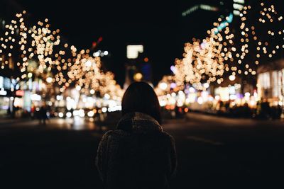 Woman standing in illuminated city at night