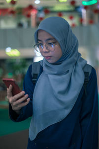 Close-up of woman wearing hijab using mobile phone