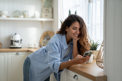 Young woman using mobile phone at home