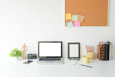 Close-up of technologies with books and wooden figurine on desk in office