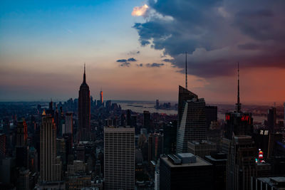 Modern buildings in city against sky during sunset