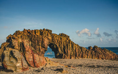 Rock formations on beach against sky