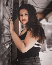 Portrait of beautiful young woman standing in mirror