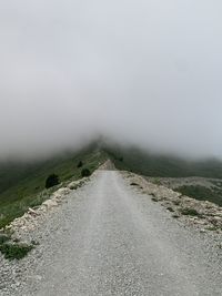 Road amidst foggy landscape against sky