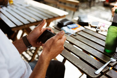 Midsection of man using mobile phone on table