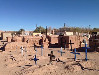 Crosses at cemetery against clear blue sky