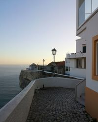 Lighthouse by sea against clear sky