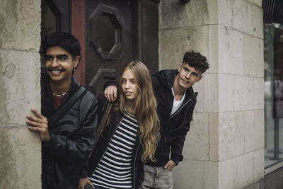 Portrait of smiling friends standing against wall