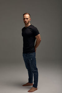 Portrait of young man standing against gray background