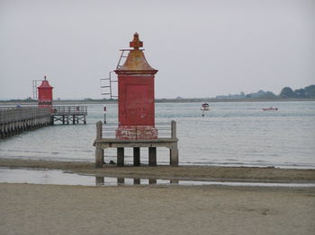 Lighthouse by sea against sky