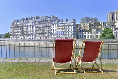 Chairs on field against buildings in city