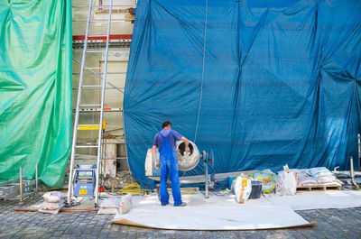 Rear view of man working while standing at construction site