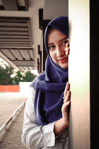 Portrait of young woman standing against wall