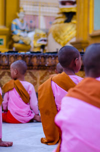 Rear view of monks sitting in temple