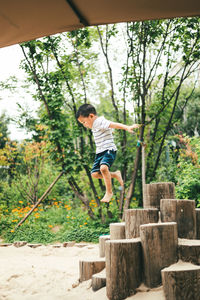Full length of boy jumping against trees