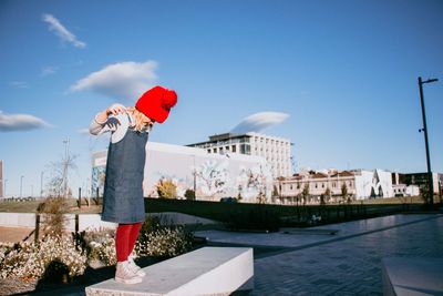 Rear view of boy standing by canal against sky