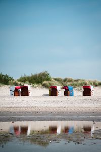 Deck chairs on beach against clear sky