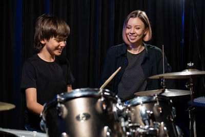 Boy playing drums by mother on stage