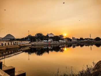 Scenic view of lake by temple against sky during sunset