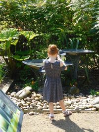 Rear view of woman standing against trees