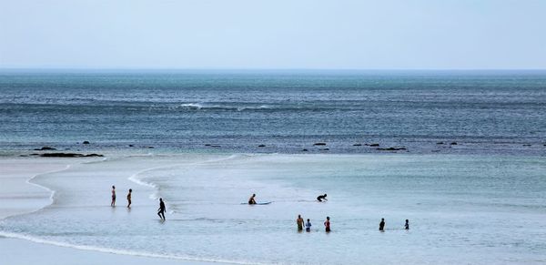 Group of people on beach against clear sky