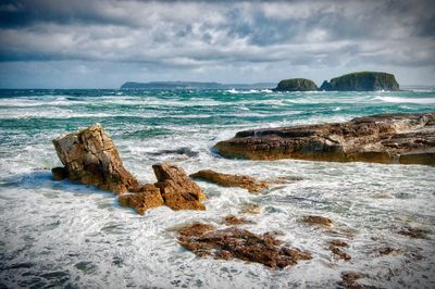 Scenic view of rocks on beach against sky