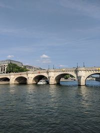 Arch bridge over river against sky in city