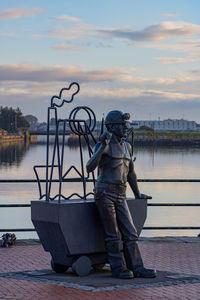 Man on pier by lake against sky during sunset