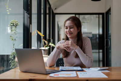 Young woman using mobile phone while sitting on table