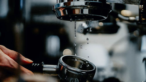 Close-up of hand holding container under coffee maker