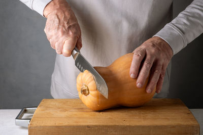 Midsection of man cutting pumpkin on table