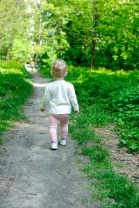 Rear view of cute girl walking on footpath
