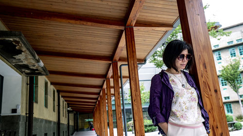 Young woman standing against building