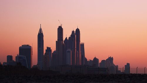 Buildings in city against sky during sunset