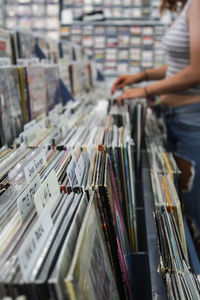 Midsection of woman buying compact discs at store