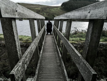 Rear view of man walking on footbridge