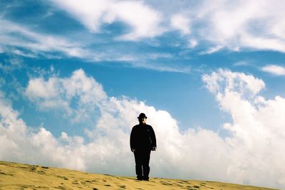 Man standing on landscape against cloudy sky